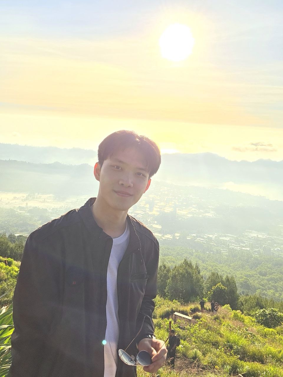 Johan Untawidjaja standing on Mount Batur in Bali at sunrise, with mist over the valley below.