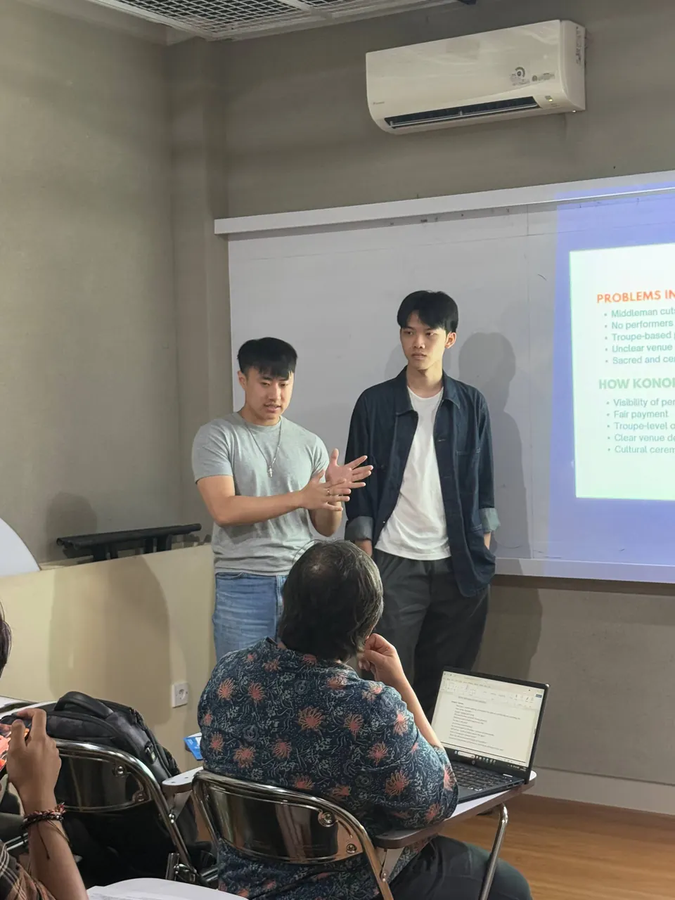 Two of the team standing at the front while a member of the audience puts a question to them