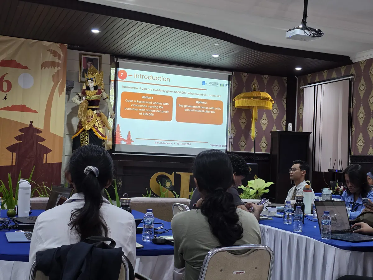 A session in Bali: attendees seated facing a projected slide, with Balinese carvings and a gilded statue in the room