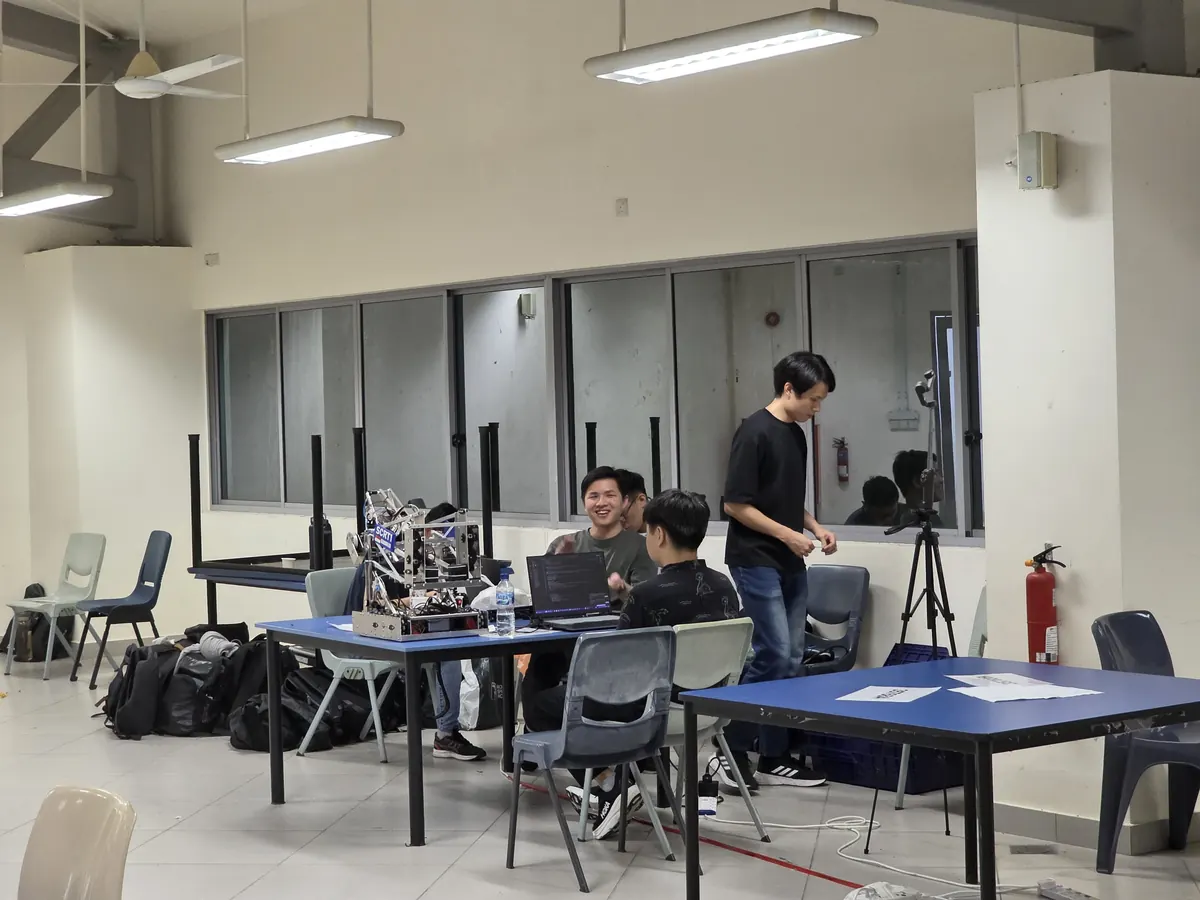 The team working on the robot at tables with laptops