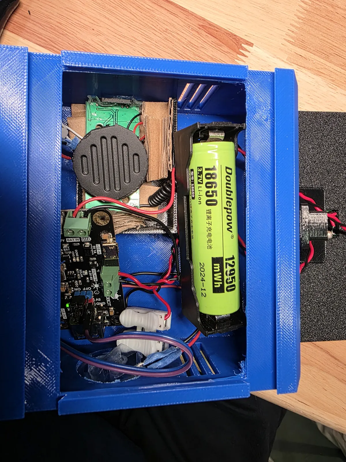 Open blue 3D-printed enclosure showing PCB, 18650 battery, speaker and wiring